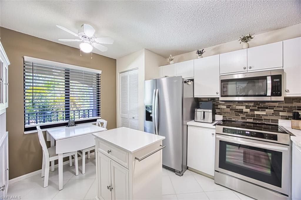 Kitchen with stainless steel appliances, a textured ceiling, backsplash, ceiling fan, and light countertops