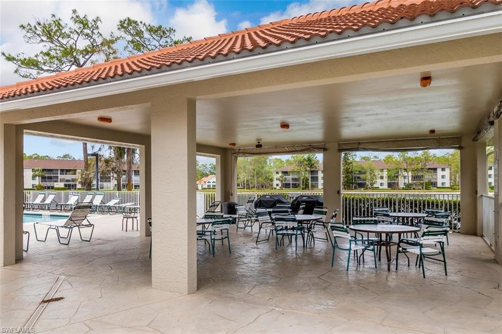 View of patio with fence, outdoor dining space, and a community pool