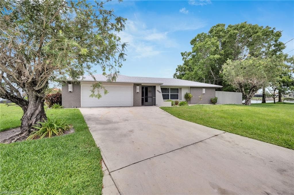 Single story home featuring a two-car garage, concrete driveway, and a manicured lawn