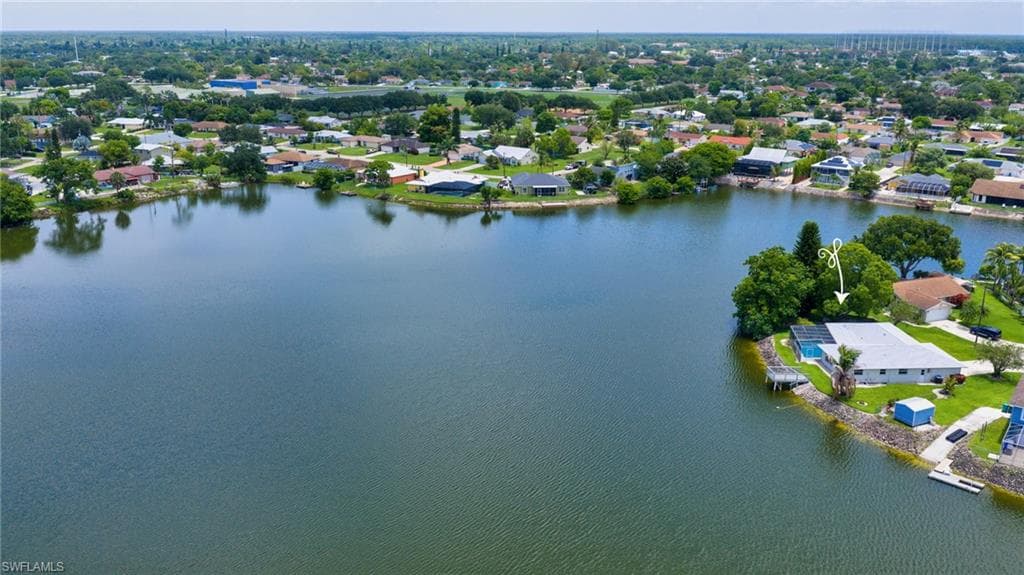 Waterfront property featuring a private dock, swimming pool, and mature landscaping