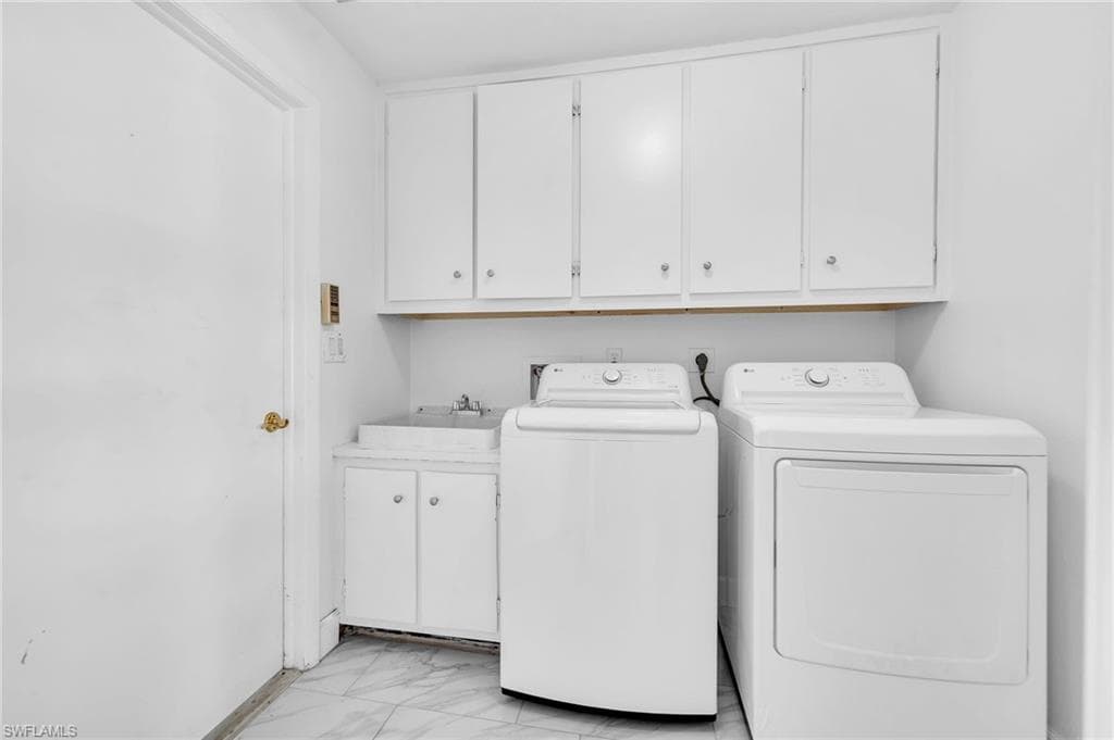 Dedicated laundry room featuring upper storage cabinetry, an integrated sink basin with lower cabinetry, and tiled flooring