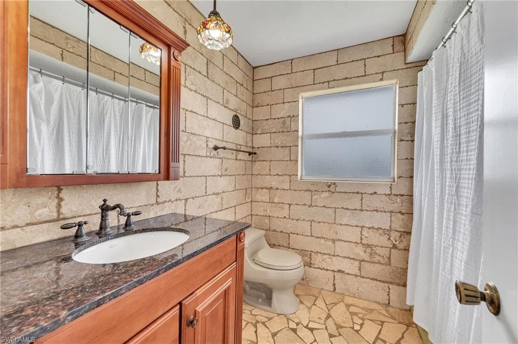 Bathroom featuring a wood vanity with dark countertop, an oval undermount sink, and dark bronze-finish fixtures