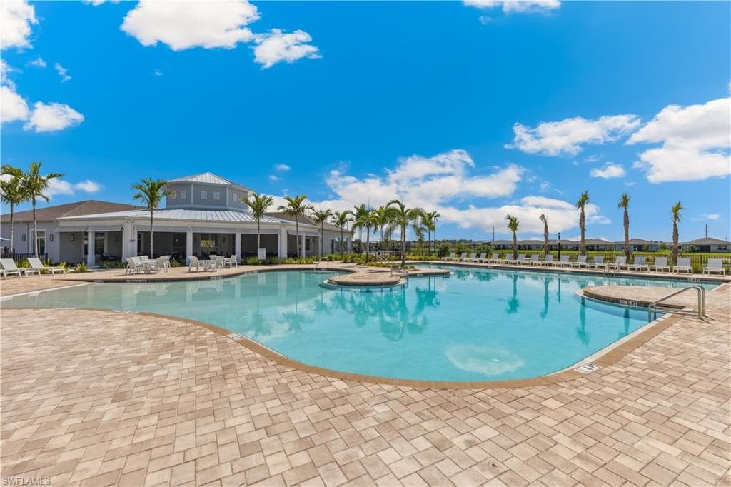 The property features a large outdoor swimming pool with a paved deck area, surrounded by palm trees