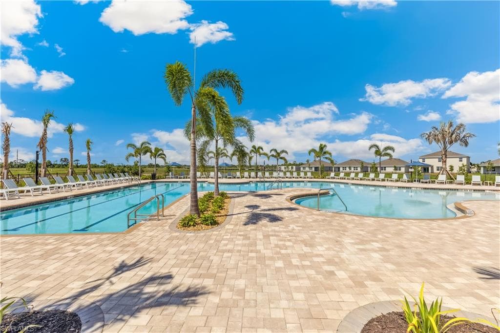 The property features a large outdoor swimming pool area with a paved deck, surrounded by palm trees and lounge chairs