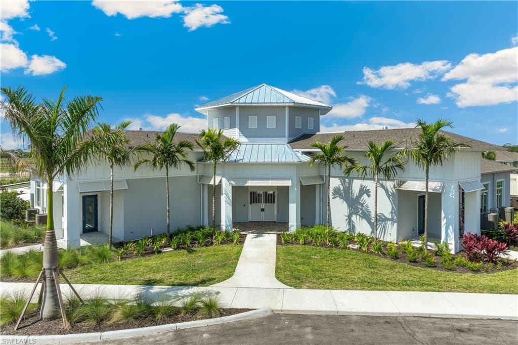 The property features a striking architectural design with a light blue and white exterior, complemented by a prominent central cupola and a light-colored metal roof