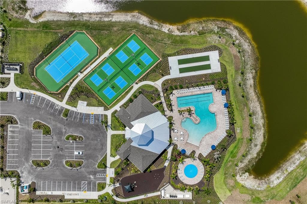 Aerial view showcasing community amenities including tennis courts, pickleball courts, a large swimming pool, and a circular spa