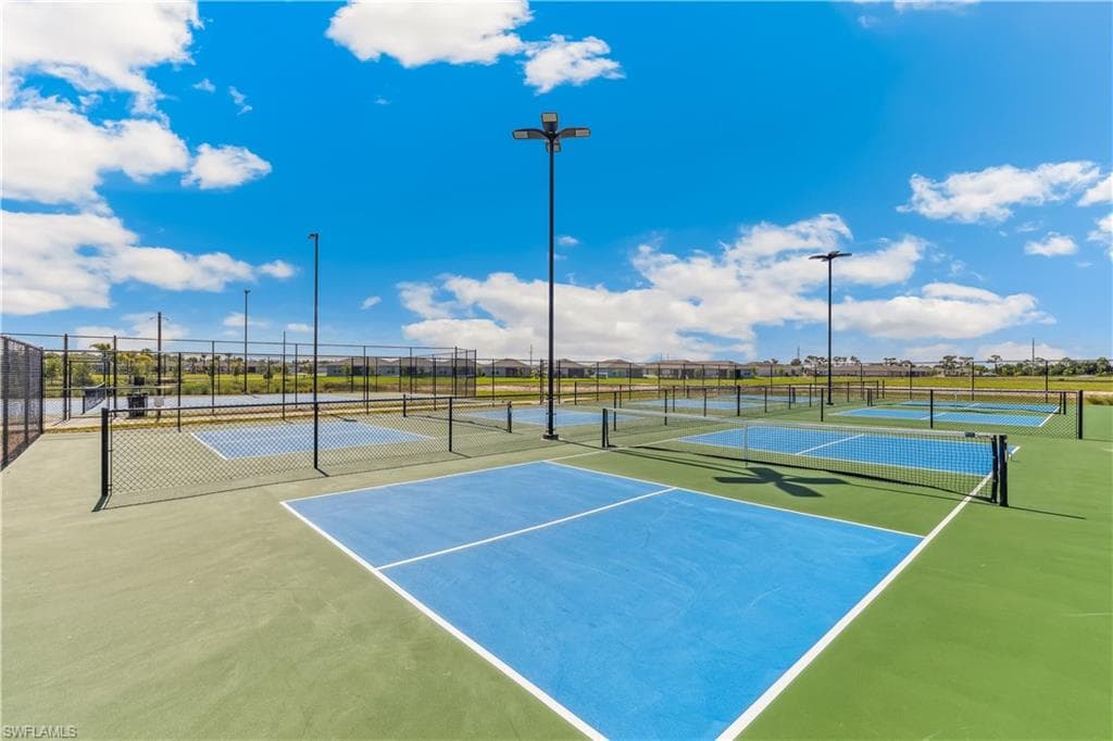 Outdoor pickleball courts featuring blue and green surfaces, surrounded by fencing and equipped with nets