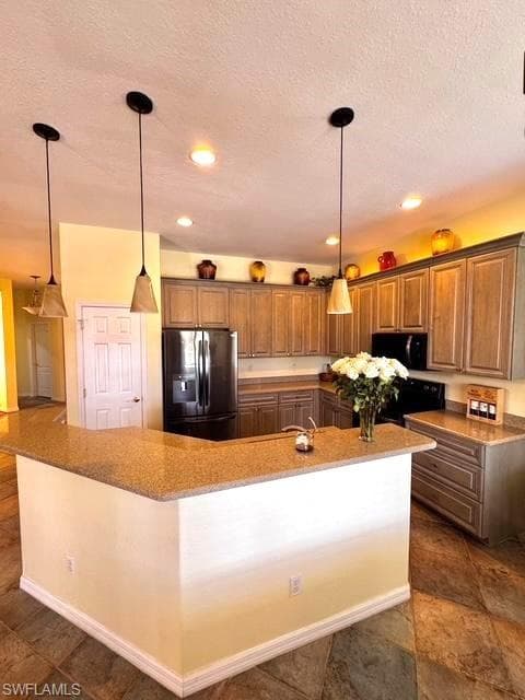 Kitchen with decorative light fixtures, refrigerator with ice dispenser, a large island, range, and a textured ceiling