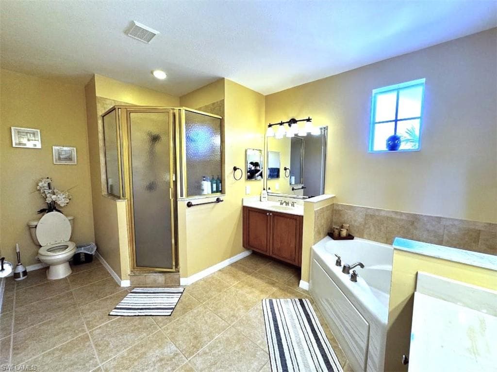 Full bathroom featuring vanity, tile patterned floors, toilet, and separate shower and tub
