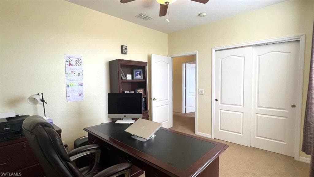 Carpeted office space featuring ceiling fan