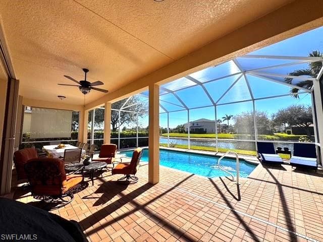 View of swimming pool featuring a water view, an outdoor hangout area, a patio area, and glass enclosure