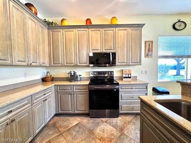 Kitchen with light stone countertops, stainless steel appliances, and sink