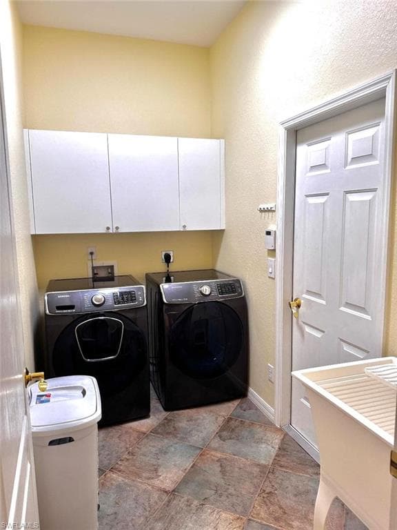 Clothes washing area featuring cabinets and washer and dryer