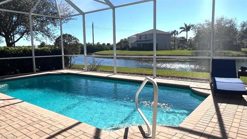 View of swimming pool with a water view, glass enclosure, and a patio area