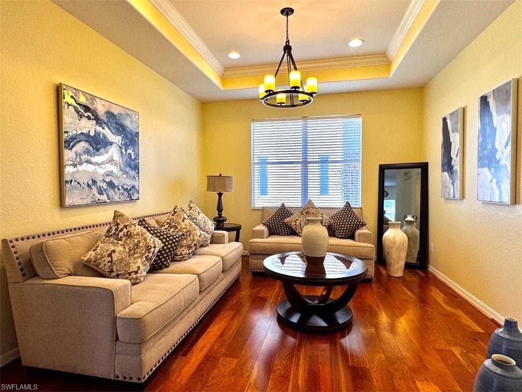 Living room with crown molding, dark wood-type flooring, and a tray ceiling