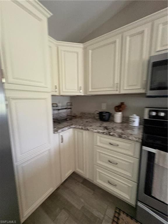 Kitchen featuring cream shaker-style cabinetry with crown molding, granite countertops, wood-finish flooring, and stainless steel appliances including a built-in microwave and oven