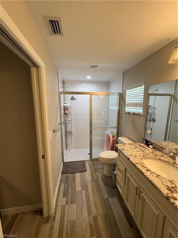 Bathroom featuring wood-look plank tile flooring and a glass-enclosed shower with subway tile surround
