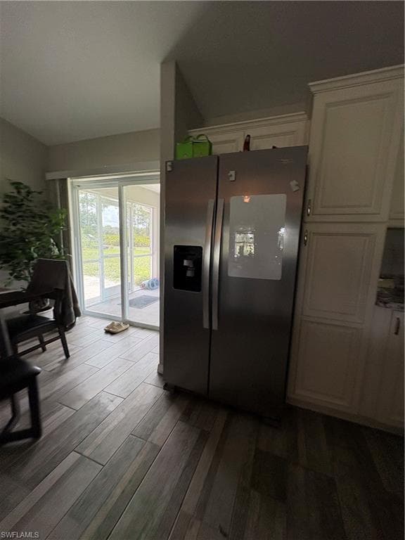 Stainless steel side-by-side refrigerator, white shaker-style cabinetry, wood-finish flooring, and glass sliding doors
