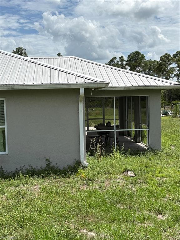 Exterior featuring a metal roof, stucco siding, and a screened patio