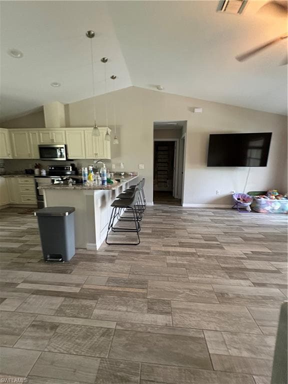 Open-concept living area with vaulted ceilings, wood-finish flooring, recessed lighting, and a ceiling fan
