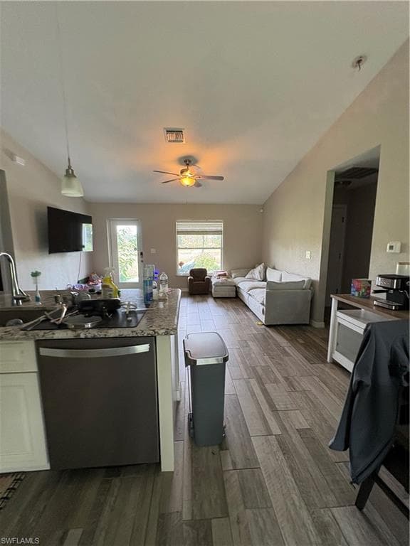 Open-concept living space featuring wood-finish flooring, vaulted ceilings, and a kitchen island with stone countertops
