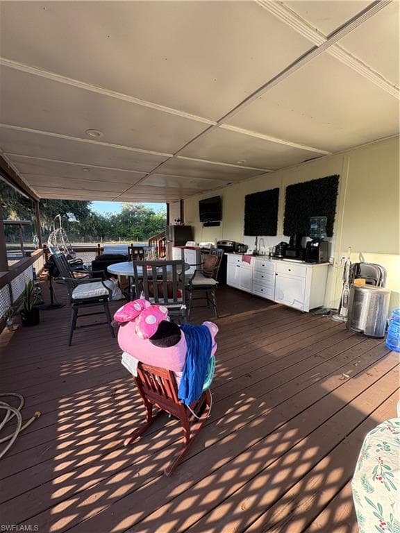 Expansive covered porch featuring wood-finish decking and a beadboard ceiling