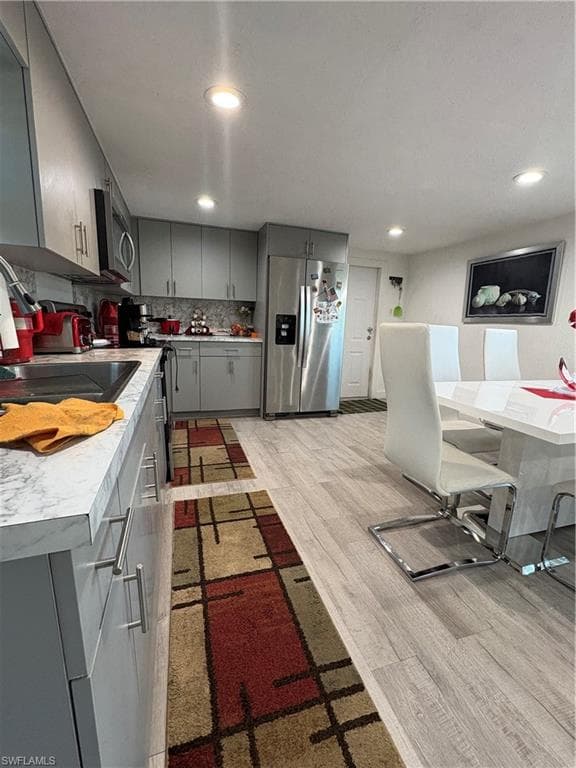 Kitchen featuring light gray cabinetry, stainless steel appliances, and light-toned wood-finish flooring