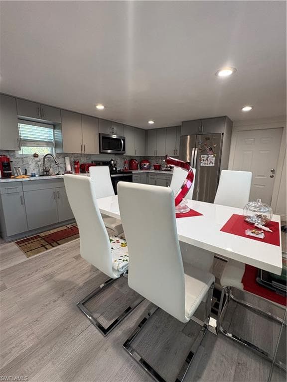 Kitchen featuring recessed lighting, light gray cabinetry, stainless steel appliances, and wood-finish flooring