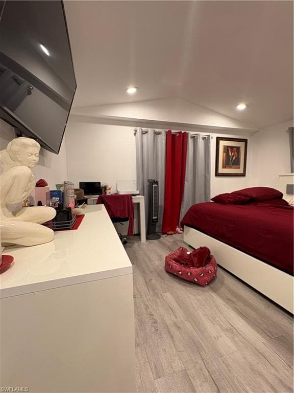 Recessed lighting illuminates this interior space featuring light wood-finish flooring and a contemporary white dresser