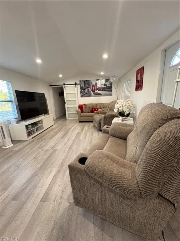 Spacious interior featuring wood-finish flooring, recessed lighting, and a modern barn door with frosted glass panels
