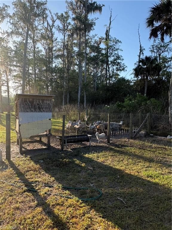 Fenced pasture area featuring a feeding trough and a wooden shelter structure