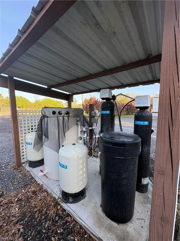 Covered water filtration system on a concrete pad with a corrugated metal roof supported by wood posts and beams