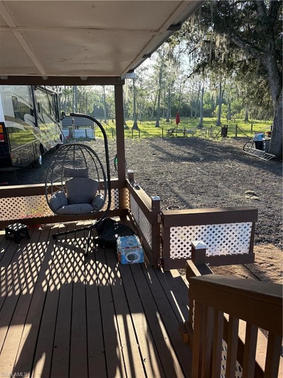 Covered outdoor deck with wood-finish flooring, lattice railing, and open-air surroundings