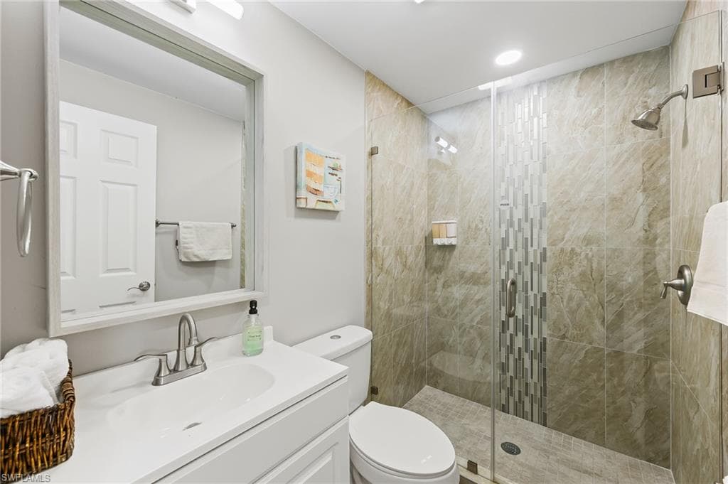 Bathroom featuring vanity, toilet, and a shower with shower door