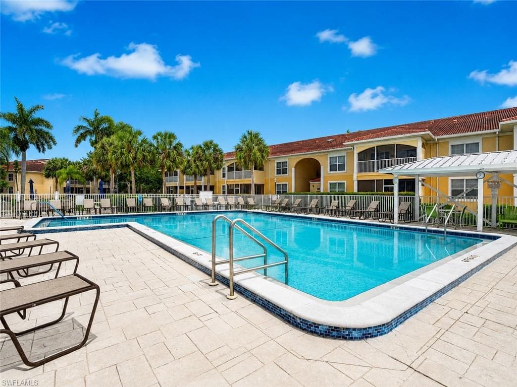 Community swimming pool featuring a tiled waterline, metal handrails, and surrounding patio pavers