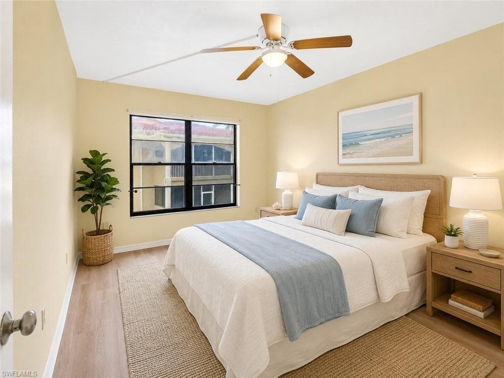 Bedroom featuring wood-finish flooring, a ceiling fan with integrated lighting, and a large window with black framing