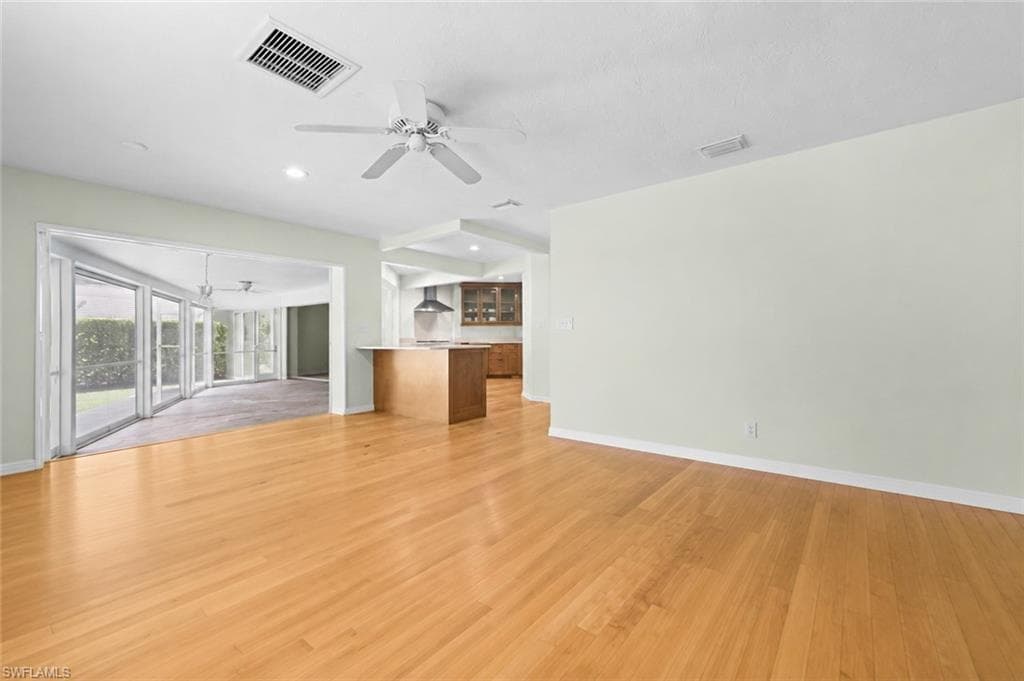 Spacious primary bedroom features warm wood flooring, abundant natural light, and direct access to the outdoor living area.