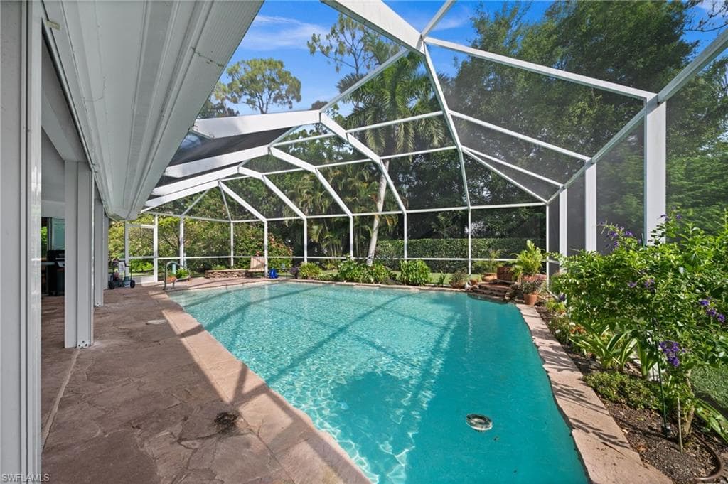 Expansive screened pool and covered lanai offer a private outdoor retreat surrounded by tropical landscaping.