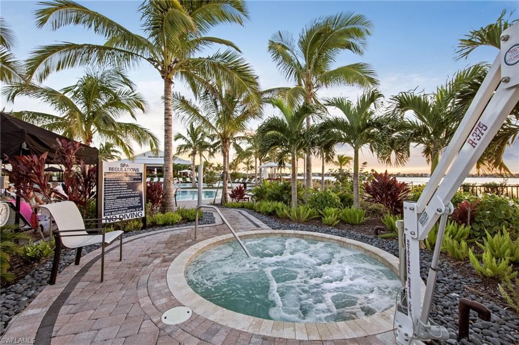 Circular spa with bubbling water, surrounded by paver flooring and lush tropical landscaping