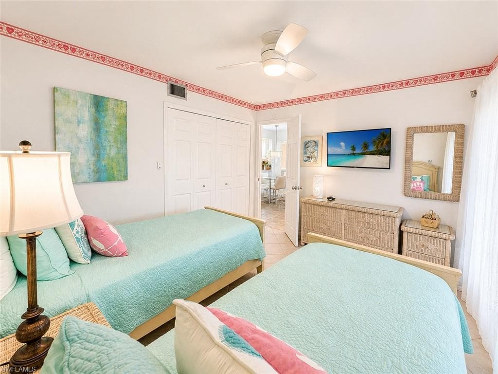 Bright bedroom featuring a ceiling fan, tiled flooring, and white bi-fold closet doors