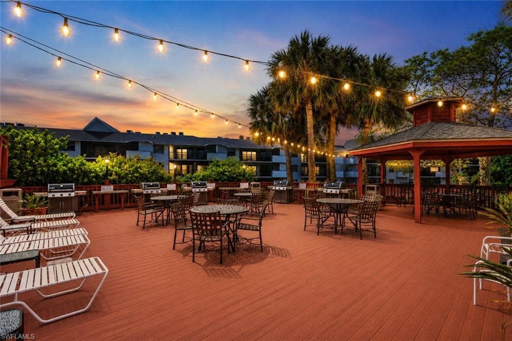 Spacious outdoor deck featuring multiple dining areas, a gazebo, and string lighting