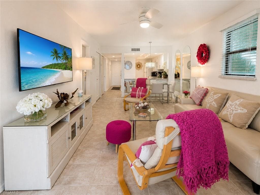 Open-concept living space featuring neutral tile flooring, a mounted television, and a ceiling fan