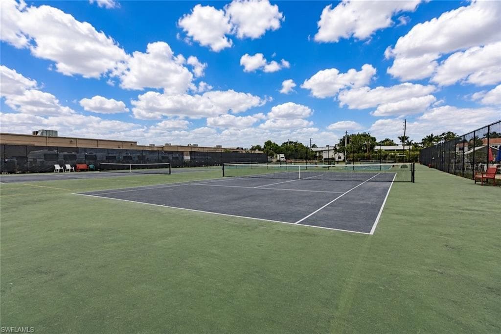 Tennis court facility featuring multiple courts with dark playing surfaces and green surrounds