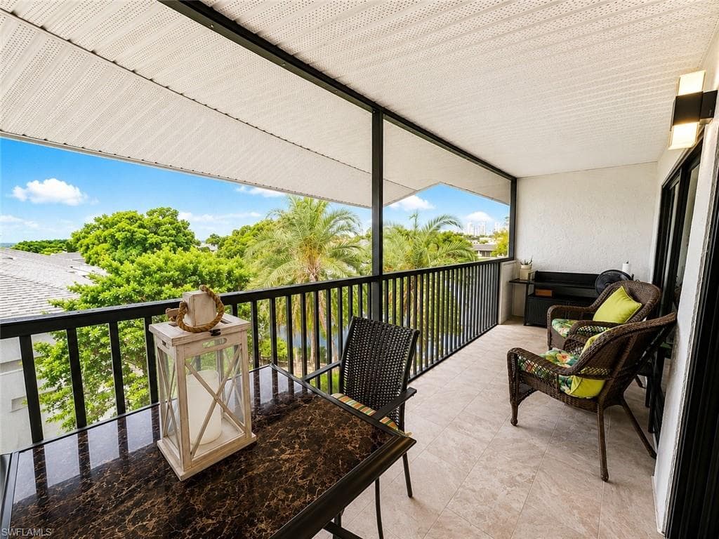 Expansive outdoor balcony featuring a neutral tile floor, black metal railing, and a textured white overhead covering