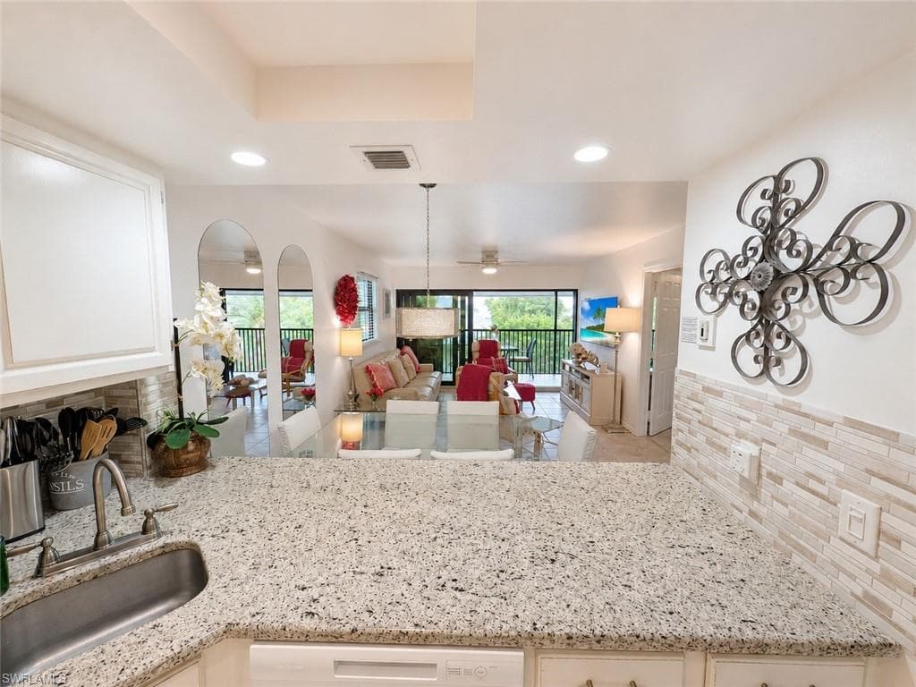 Kitchen featuring granite countertops, a stainless steel sink with a gooseneck faucet, white cabinetry, and a subway tile backsplash