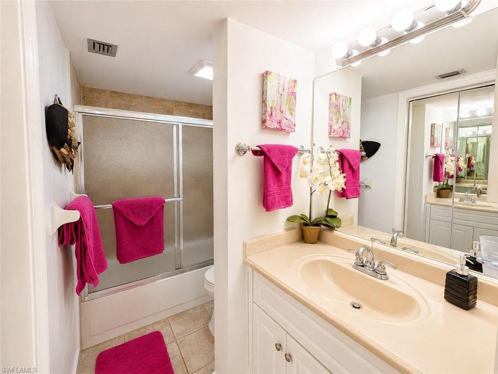Bathroom featuring a single vanity with integrated sink, white cabinetry, and a full-width mirror with overhead lighting