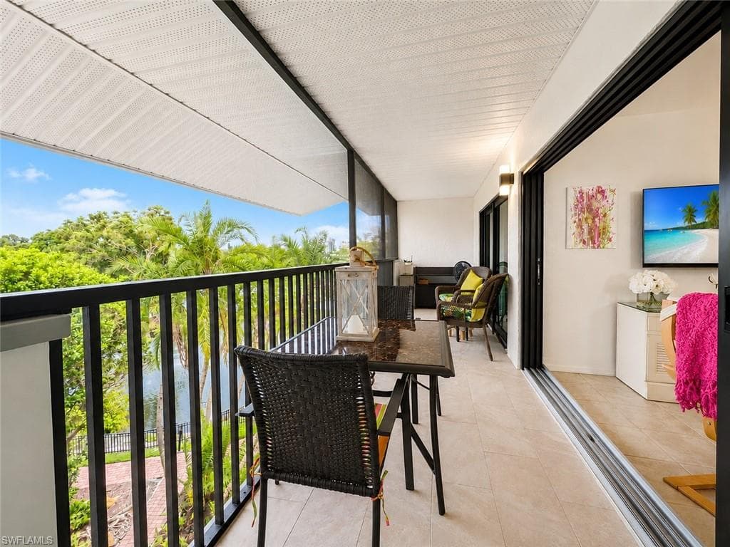 Expansive balcony featuring light-toned tile flooring, black metal railings, and a white perforated ceiling