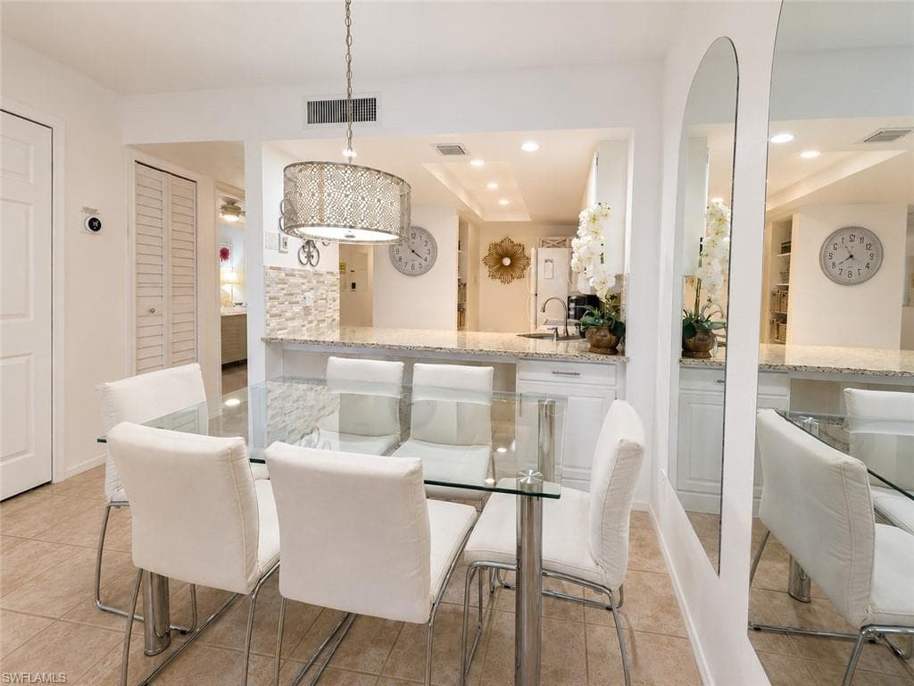 Open-concept dining area featuring tile flooring, a decorative pendant light fixture, and a pass-through counter with a stone-finish surface