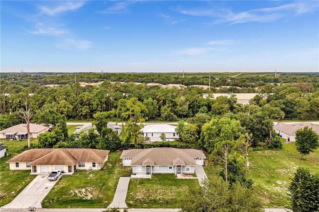 Duplex property featuring a neutral exterior, paved driveways, and surrounding green spaces
