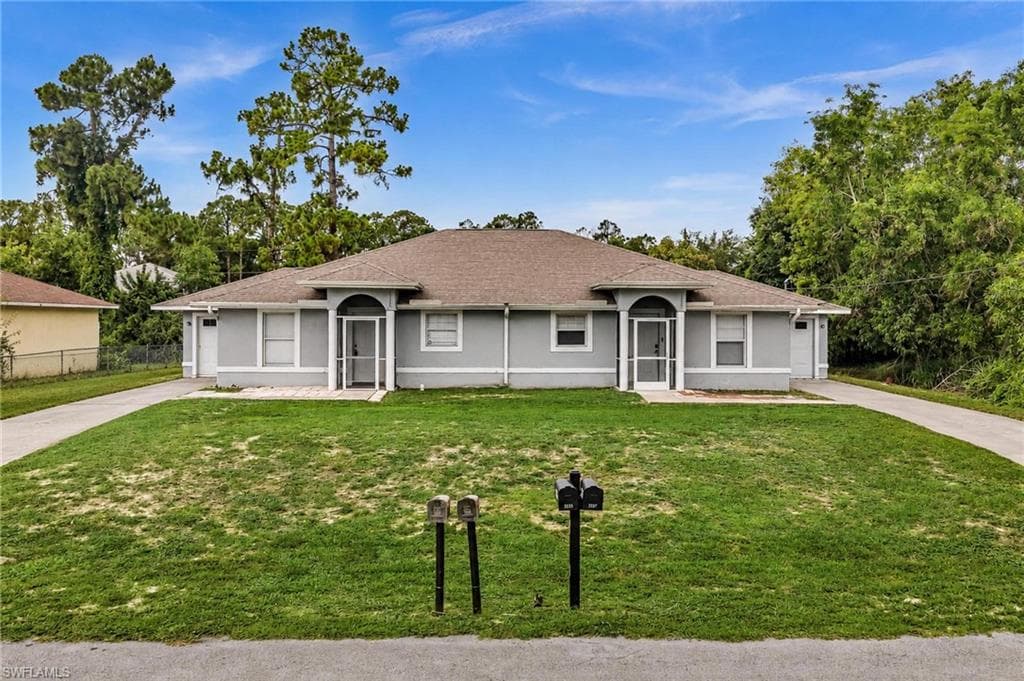 Duplex property featuring a light gray exterior with white trim, dual arched screen entries, and individual garages